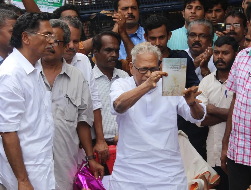 ഐക്യമലയാളസ്ഥാനത്തിൻ്റെ നിയമസഭാ മാർച്ചിൽ ഡോ.പി. പവിത്രൻ്റെ ‘മാതൃഭാഷയ്ക്കു വേണ്ടിയുള്ള സമരം’ എന്ന പുസ്തകം വി.എസ്. അച്യുതാനന്ദൻ പ്രകാശനം ചെയ്യുന്നു. പുസ്തകം ഏറ്റുവാങ്ങിയ വി. മധുസൂദനൻ നായർ സമീപം.