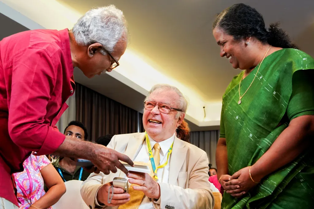 രാധാകൃഷ്ണൻ എം.ജി, ആർ. പാർവതീദേവി എന്നിവർ ക്രിസ്റ്റോഫ് സനൂസിക്കൊപ്പം, 2023-ലെ iffk വേദിയിൽ. 25 വർഷം മുമ്പത്തെ ഒരു iffk-യിലാണ്, രാധാകൃഷ്ണൻ എം.ജിയുടെയും പാർവതീദേവിയുടെയും പിതാവ് പി. ഗോവിന്ദപിള്ളയും സനൂസിയും തമ്മിൽ കമ്യൂണിസത്തെക്കുറിച്ച് സംവാദം നടന്നത്. കാൽനൂറ്റാണ്ടിനുശേഷം മറ്റൊരു iffk വേദിയിൽ പി.ജിയുടെ മക്കൾ സനൂസിയെ കാണുമ്പോൾ, അത് 1998-ലെ ആ സംവാദ ദൃശ്യത്തിന്റെ അർഥപൂർണമായ തുടർച്ചയായി മാറുന്നു.