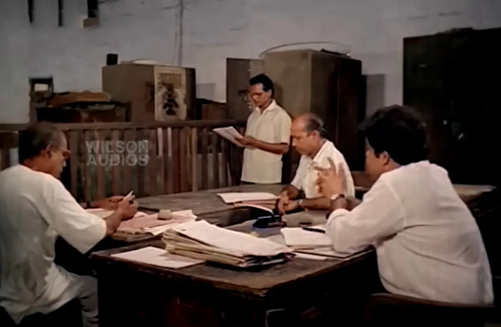 ‘വാസ്തുഹാ​ര’യിൽനിന്ന്. ഈ സിനിമയിൽ മറ്റൊരു ലോകം കൂടി നിലനിൽക്കുന്നുണ്ട് - ചലനമില്ലാത്ത (stable) ഒരു ലോകം. ഓഫീസുകളിൽ ഫയലുകൾക്കു മുൻപിൽ ഇരിക്കുന്ന ഉദ്യോഗസ്ഥരും, സ്വന്തം വീടുകളുടെ പരിസരങ്ങളിൽ ഉറച്ചുനിൽക്കുന്ന സ്വത്തുടമകളും (സിനിമയിൽ ഇത് സ്ത്രീകളാണ് ) ഇവരുടെ ജീവിതം സഞ്ചാരത്തിലല്ല; സ്ഥിരതയിലാണ്. 